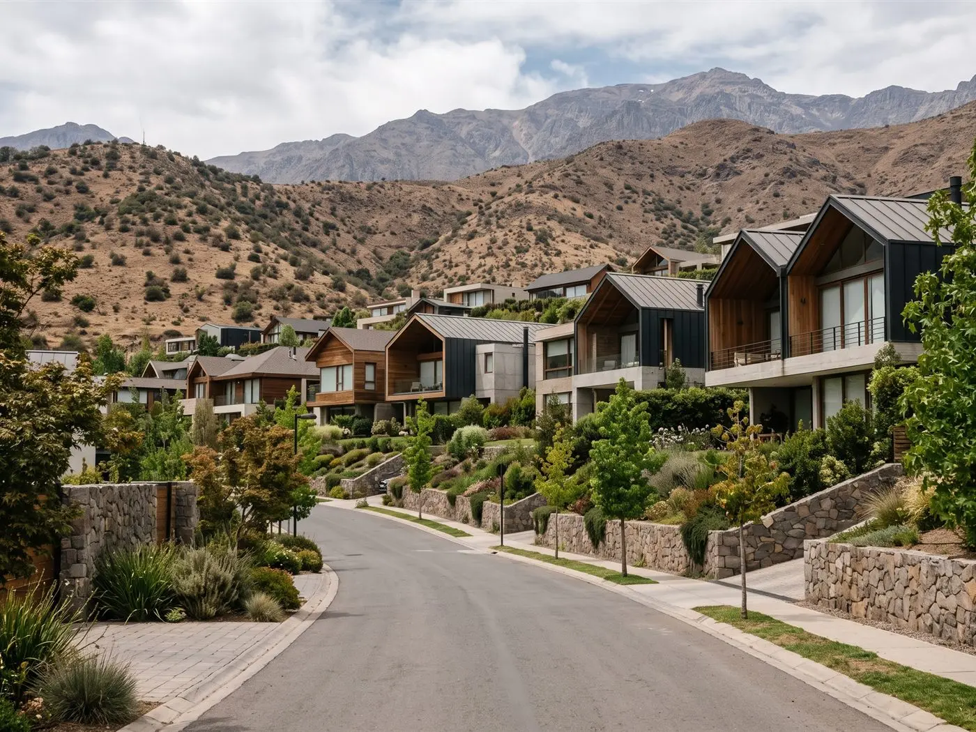 Casas de un condominio en la ladera de Lo Barnechea, con cerros secos y la cordillera detrás