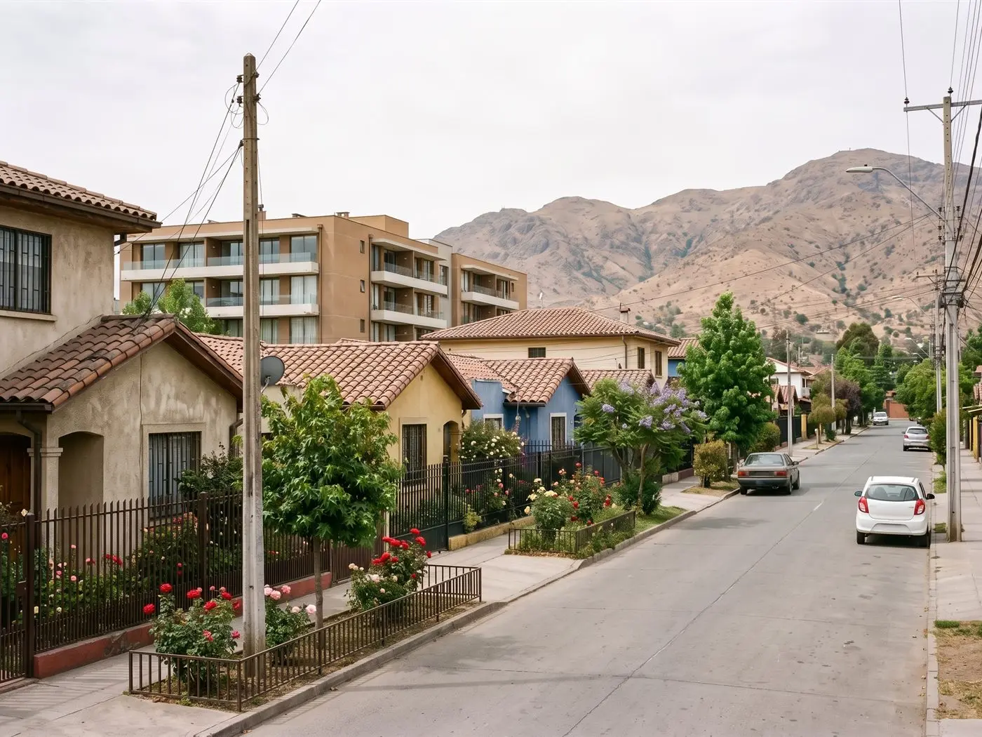 Calle tranquila de San Bernardo con casas, antejardines con rosas, un condominio nuevo y cerros al fondo